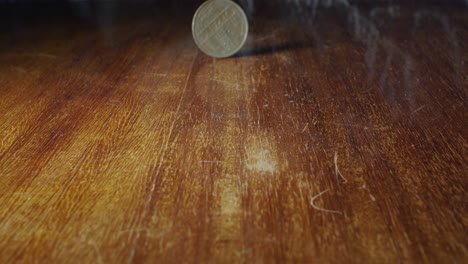 closeup of 10 francs coin flipping on wooden table, static, slow