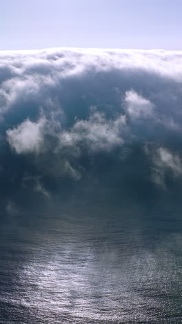 thick white fog spreading to the coastline from water. amazing cloudscape of haze on sunny summer day. aerial view. vertical video