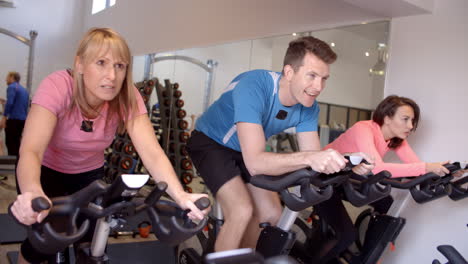 Side-view-of-a-spinning-class-on-exercise-bikes-at-a-gym