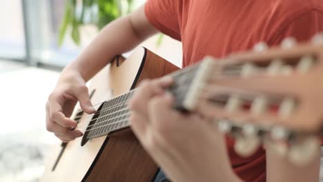 close up of young guy playing guitar in his room. he is sitting on the couch and passionately enjoying the music. 4k video