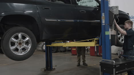 auto mechanics put a vehicle up on a hydraulic lift in a repair shop