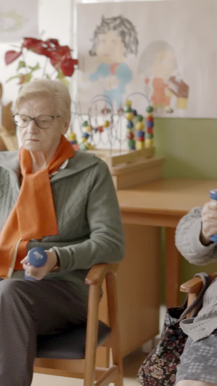 Seniors exercising in a nursing home using pedals and dumbbells