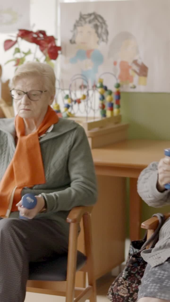 Seniors exercising in a nursing home using pedals and dumbbells