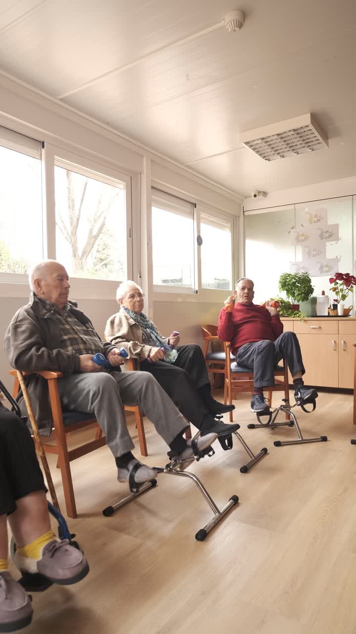 Senior men and women doing pedal exercises and lifting dumbbells at rehabilitation center