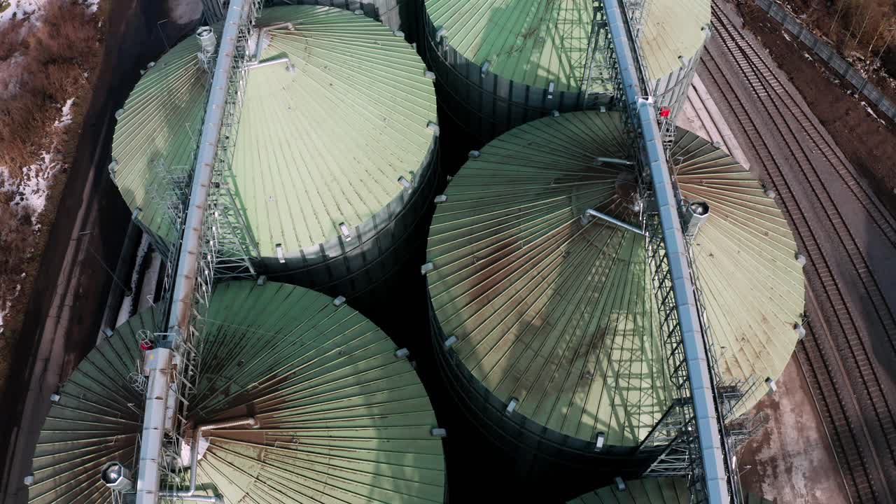 위에서 볼 수 있는 금속 실로: 곡물을 저장하고 가공하기 위한 대형 컨테이너, 농장 내의 은색 곡물 엘리베이터, 위에서 보이는 저장 크, 곡물이 있는 실로.