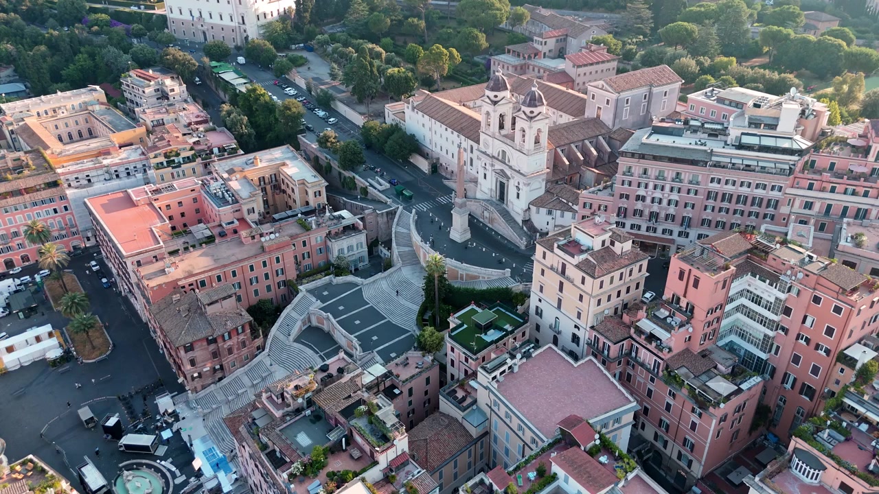 La Scalinata di Piazza di Spagna e la chiesa di Trinità dei Monti si ergono sopra i circostanti condomini mentre un drone mattutino sorvola il quartiere.