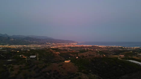 Glowing-lights-of-coastal-city-at-dusk-time,-aerial-view-of-Spain