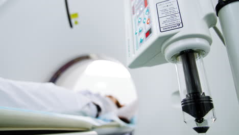 black forcer in glass reservoir of the equipment goes slowly down. mri scanning procedure began. patient lies on the bed of computed tomography machine. low angle view.