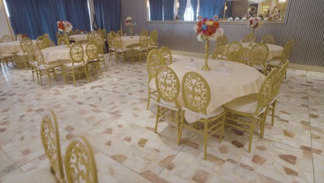 luxury chairs with flowers in vases on top of it ready for guests in a banquet