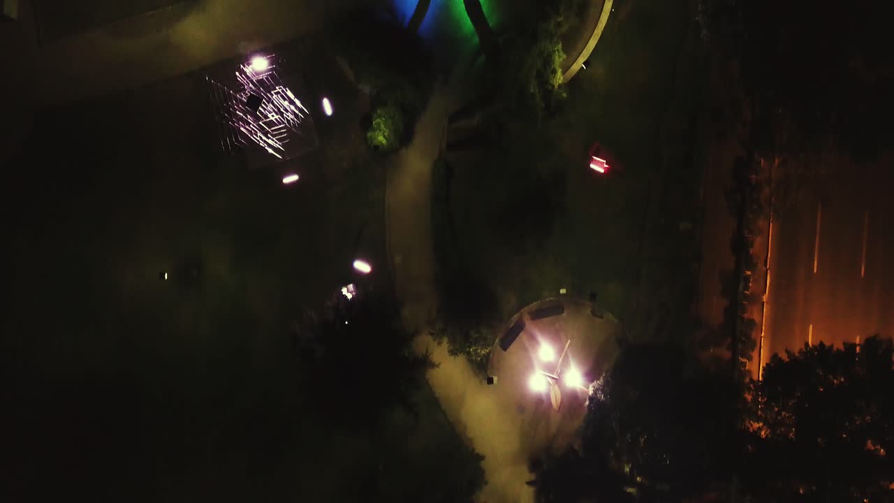 Top view park at the night flying smoothly thru pathways calm and empty place behind roads and buildings [4K4096x2160] 23,976fps