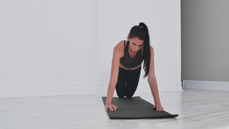 Young-sexy-brunette-woman-in-sportswear-performs-pushups-kneeling-at-home-on-a-rug