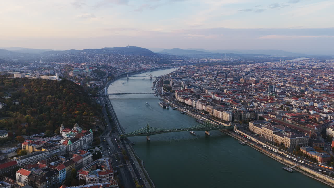 The Danube River winds between Buda and Pest, connecting iconic bridges and neighborhoods in a golden evening panorama