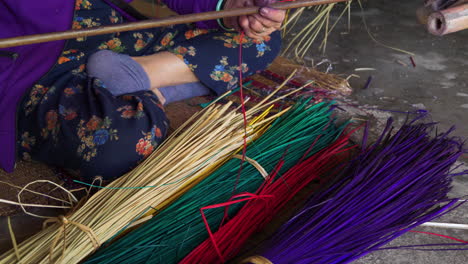 woman making a carpet from colorful straws