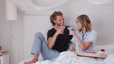 pareja bebiendo champán en la cama para celebrar el cumpleaños o el día de san valentín