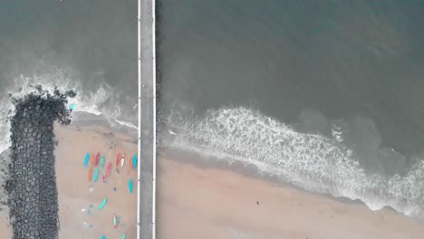 4k aerial top down tripod shot of a shipping port pier on a sunrise with monsoon clouds covered near rock beach shot with a drone, pondicherry, india