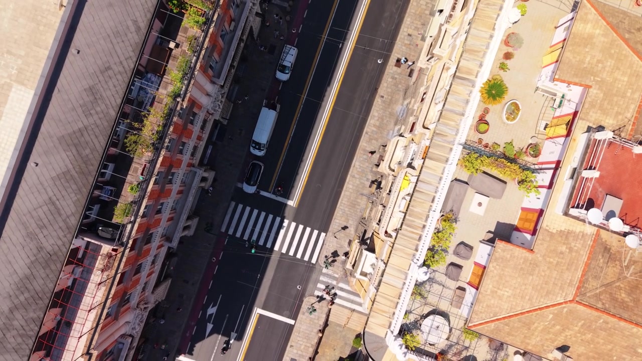 Un drone si alza verticalmente sopra una strada del centro di Genova in una drammatica vista dall'alto