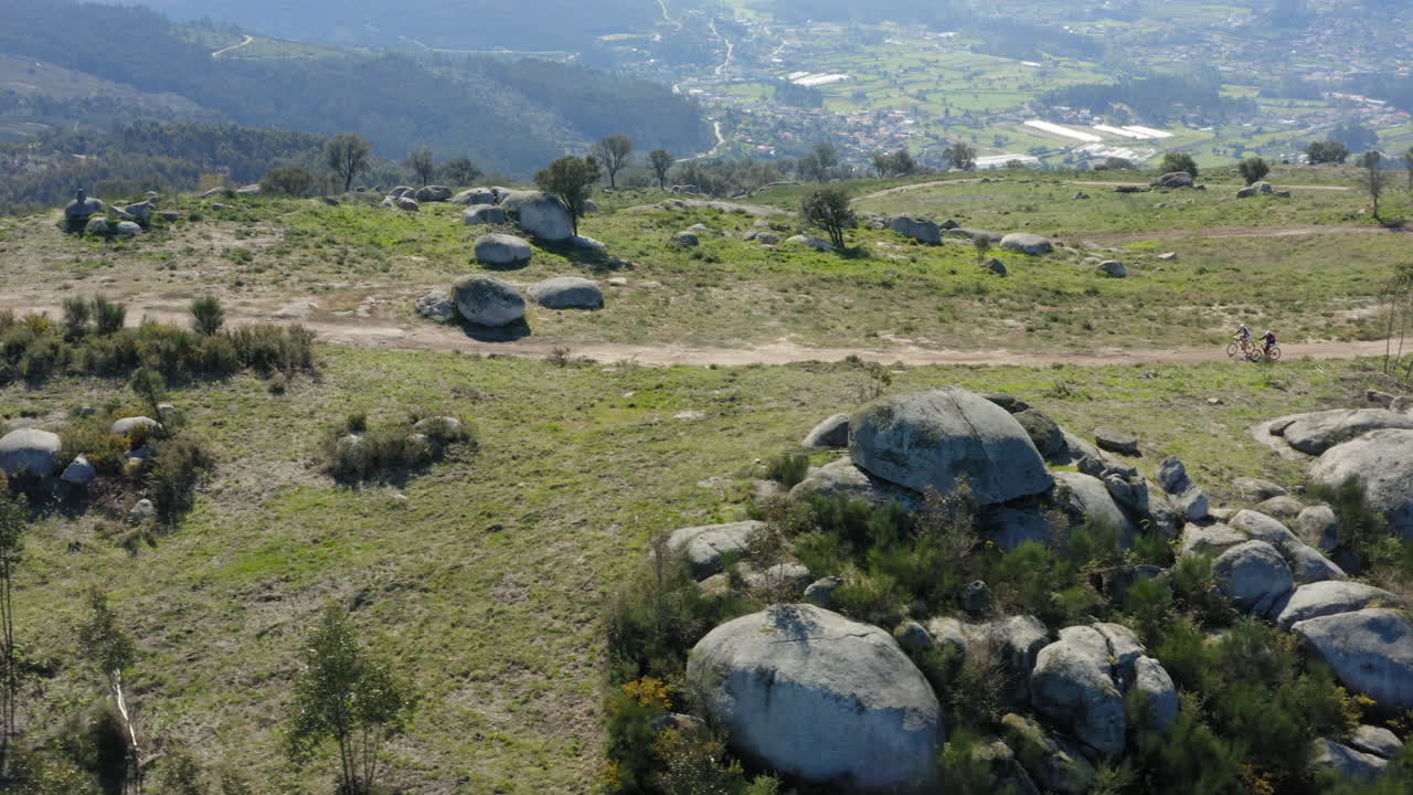 seguimiento aéreo de ciclistas que recorren la cima de la montaña alto minho, portugal - toma de diapositivas