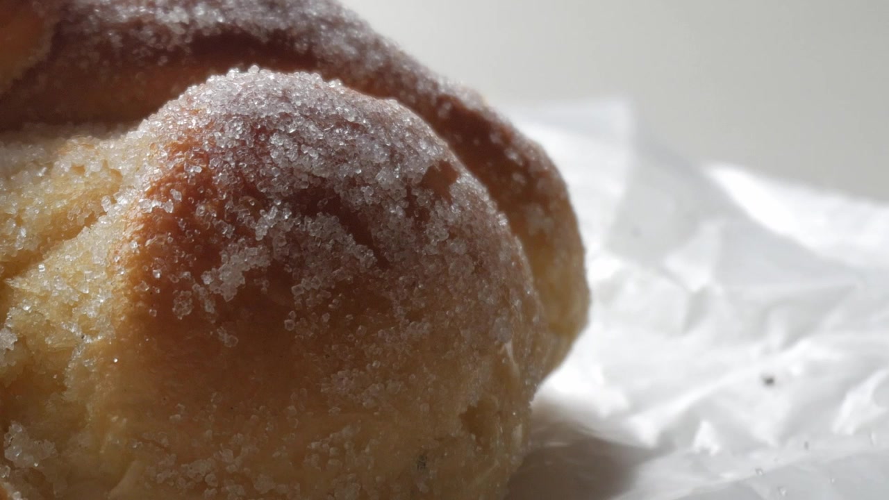 Pan dulce llamado Pan de Muerto, disfrutado durante las festividades del Día de Muertos en México - primer plano con paneo lento hacia arriba