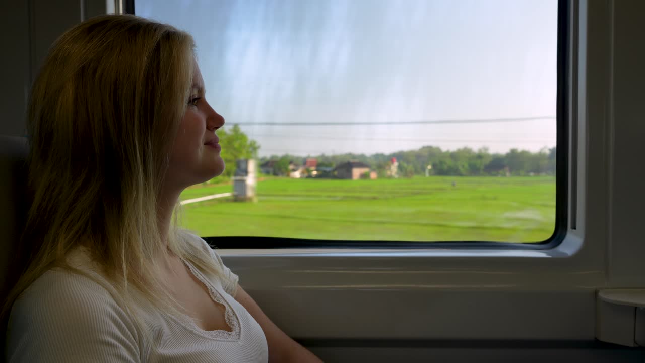 Female traveler in business class train enjoy scenery of Indonesia countryside