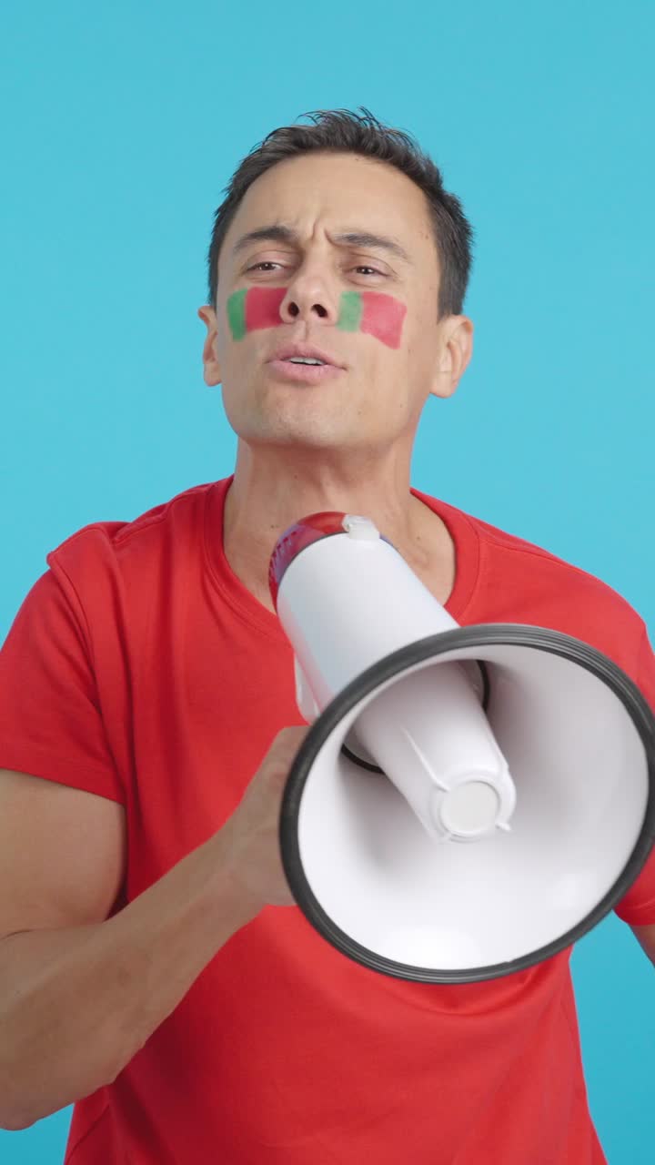 Excited man with portuguese flag on face using a megaphone