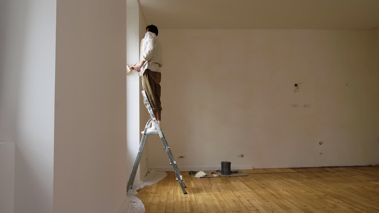 hombre en escalera aplicando pintura limewash en la pared de la casa con trazos de pincel