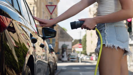 girl charging an electric car at a station on the city street, low angle shot