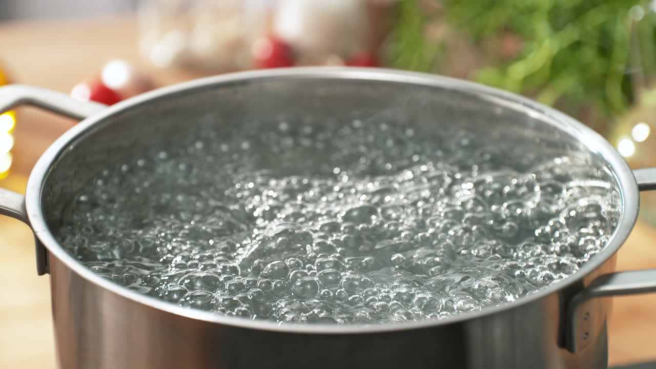 Water for Soup or Pasta Boiling in a Stainless Steel Pot in the Sunny Kitchen - Steam Rises from the Hot Bubbling Liquid