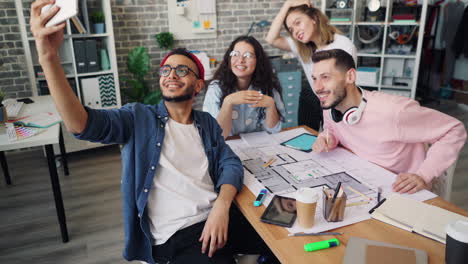 diverse group of young professionals taking a selfie in a modern office