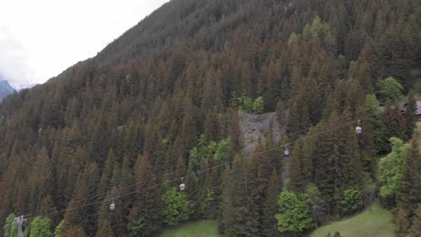 aerial of a gondola in a grassy valley leading to a small town