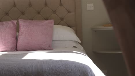 light beaming through hotel room window onto luxury country bed with comfy pink pillows ready for weekend vacation