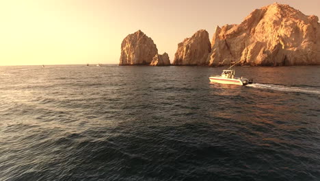 Imágenes-De-Drones-En-El-Arco-De-Cabo-San-Lucas,-México,-Siguiendo-Un-Barco-Navegando-Por-El-Agua