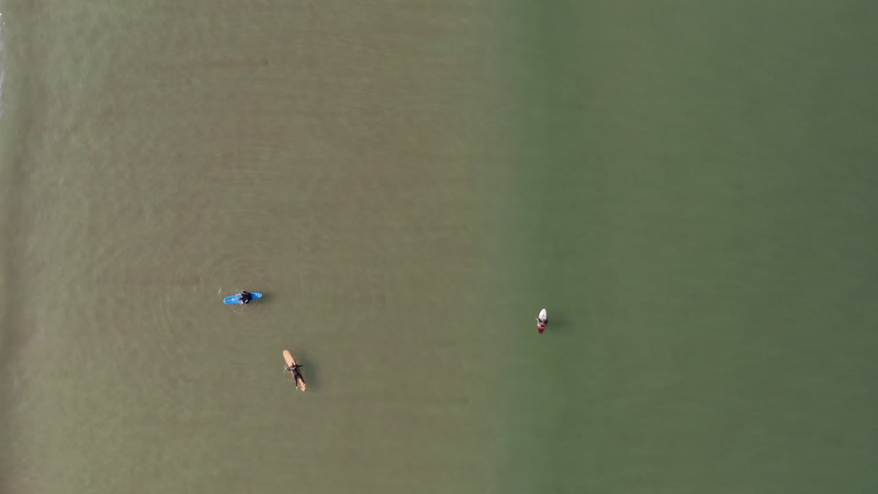 여러 명의 서퍼들이 노를 저으며 부서지는 파도의 움직이는 공중 샷