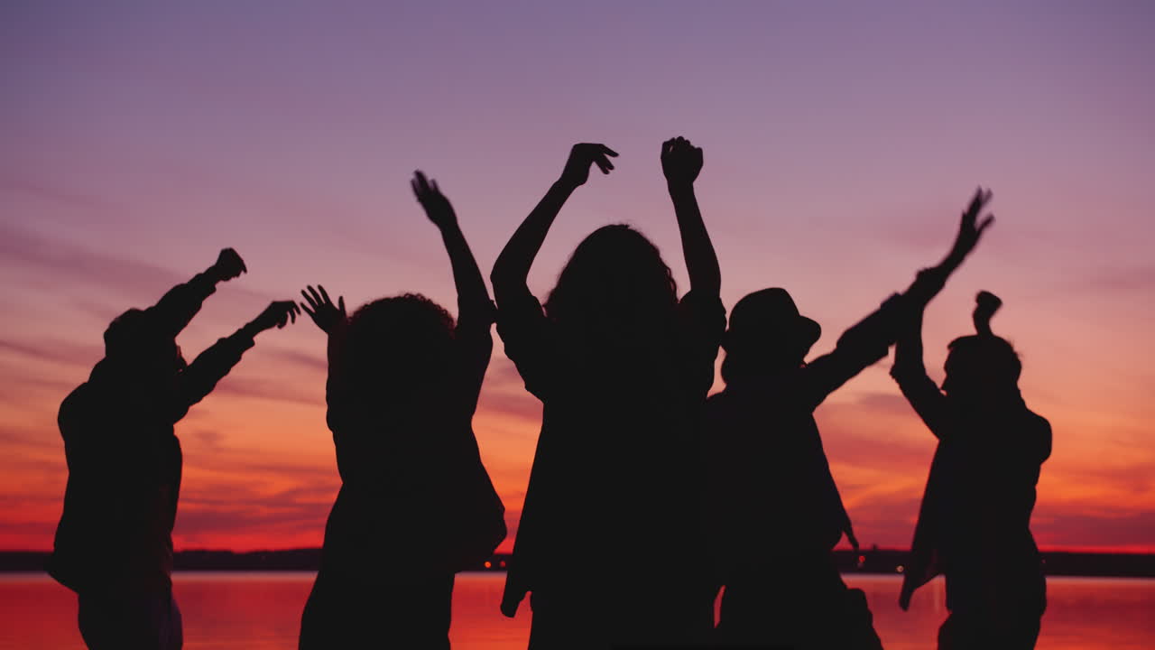 Silhouette of Friends Dancing at Sunset on the Lake