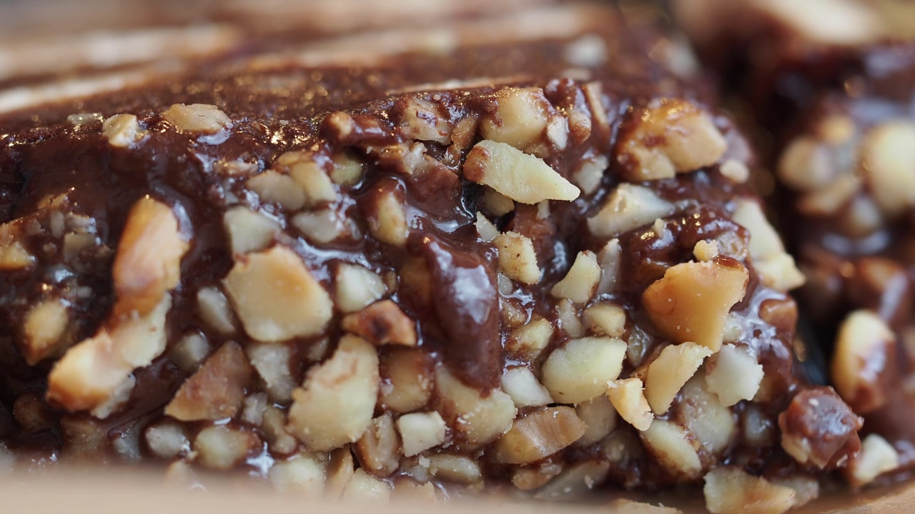 Slicing a Rich Chocolate Dessert Topped with Chopped Nuts