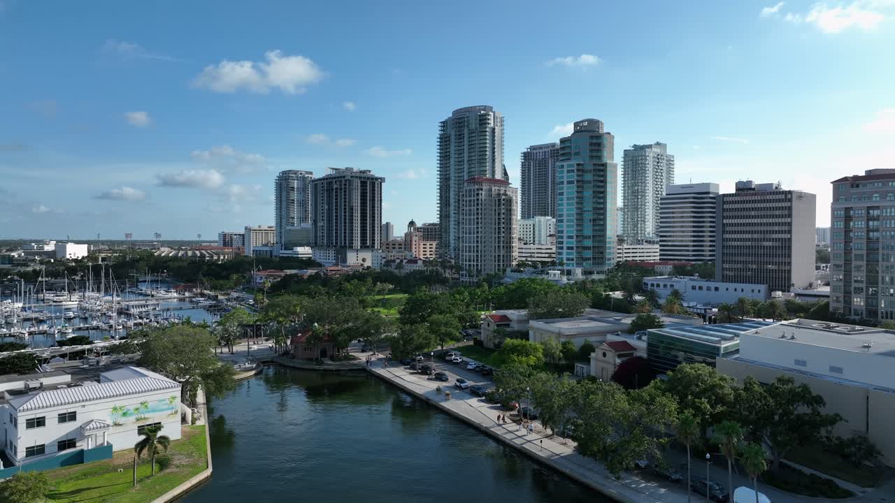 Beautiful aerial view of St. Petersburg’s waterfront and marina. High-rise buildings, calm waters and docked boats create a peaceful coastal city scene captured during a clear sunny day.