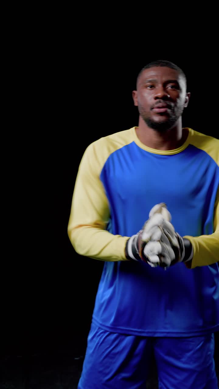 Vertical video: African American man in kit adjusting gloves on camera preparing to move in studio