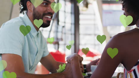 animación de iconos de corazón sobre una pareja afroamericana que se sostiene de la mano, en cámara lenta.