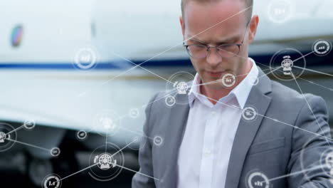 animación de una red de iconos digitales sobre un hombre de negocios caucásico comprobando el tiempo en un aeropuerto