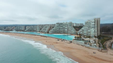 Dolly-Aéreo-Fuera-Del-Mar-Y-La-Costa-De-Arena-Cerca-De-La-Piscina-Y-Resorts-Más-Grandes-Del-Mundo-En-Algarrobo,-Chile