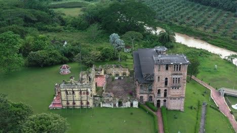 reverse reveal shot capturing british colonial ruins, riverside incomplete architecture structure old scottish folly, kellie's castle on green lawn at batu gajah, kinta district, perak, malaysia.
