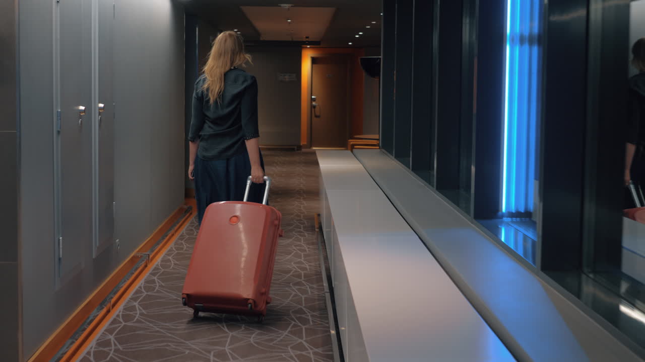 Kvinde med trolleykuffert på hotelgangen