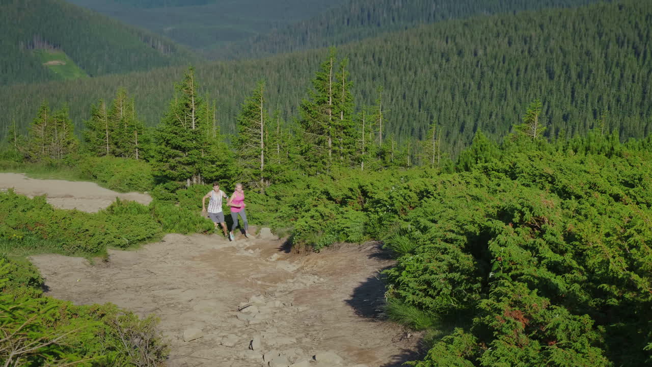 Äärimmäinen juoksu- ja kestävyyskoe. Mies ja nainen juoksevat vuoristopolkua ylös 4K video.