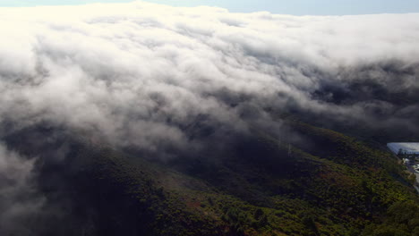 Dense-fog-rolling-across-the-hills,-aerial-view