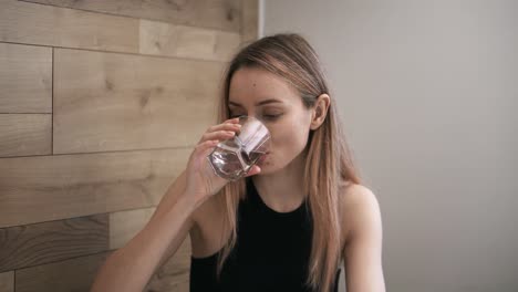 Schlanke-Frau-Nimmt-Nahrungsergänzungsmittel-Vom-Tisch-Und-Trinkt-Ein-Glas-Wasser