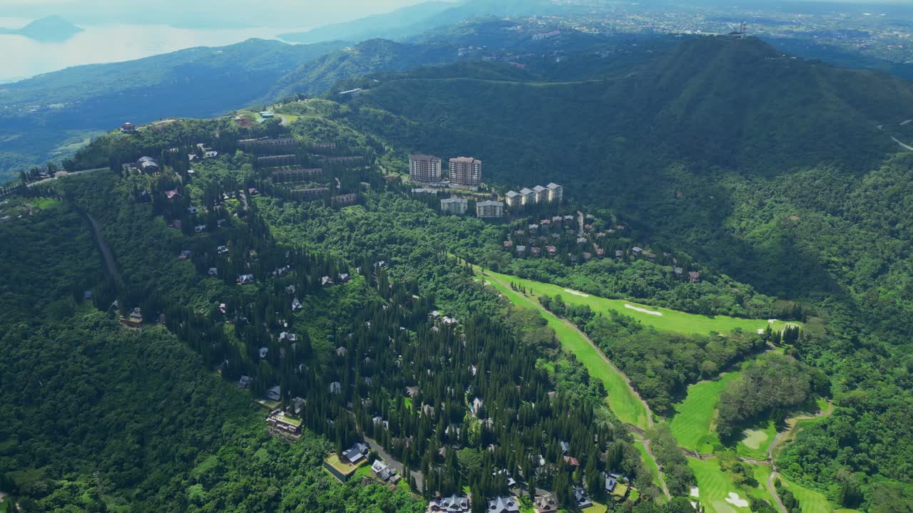 A wide high elevated aerial of The Woodlands Tagaytay Highlands showing pine trees, hillside homes, and winding roads in Batangas, Philippines