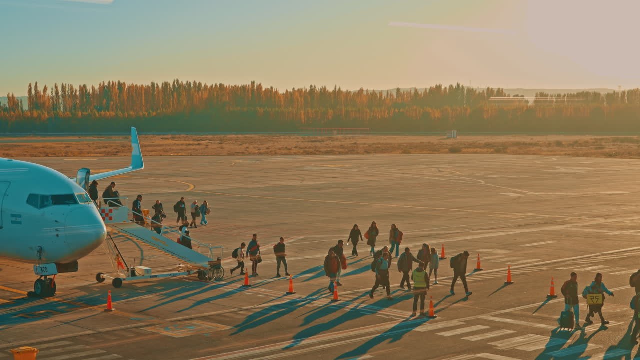 Passengers Boarding an Airplane on the Tarmac at Sunset