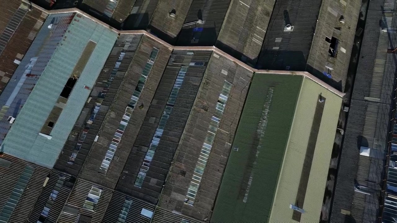 Old British industry warehouse rooftop aerial Birdseye view over huge factory asbestos roofing