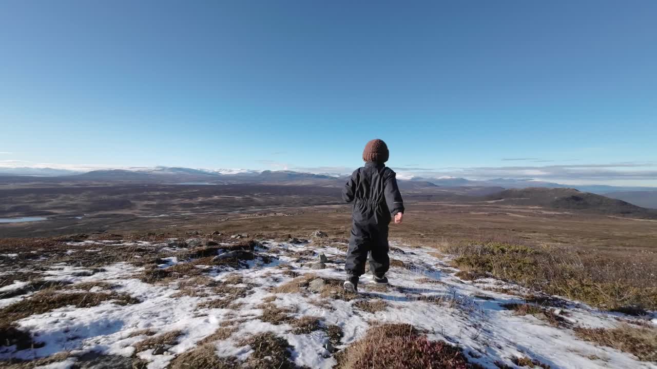 vista trasera de un niño corriendo por la montaña a finales de otoño y aire fresco con vistas espectaculares