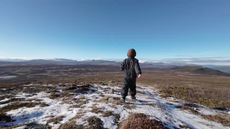 Rear-view-of-child-running-down-mountain-late-autumn-and-crisp-air-with-spectacular-views