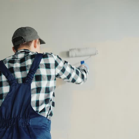 male builder paints wall with roller 1